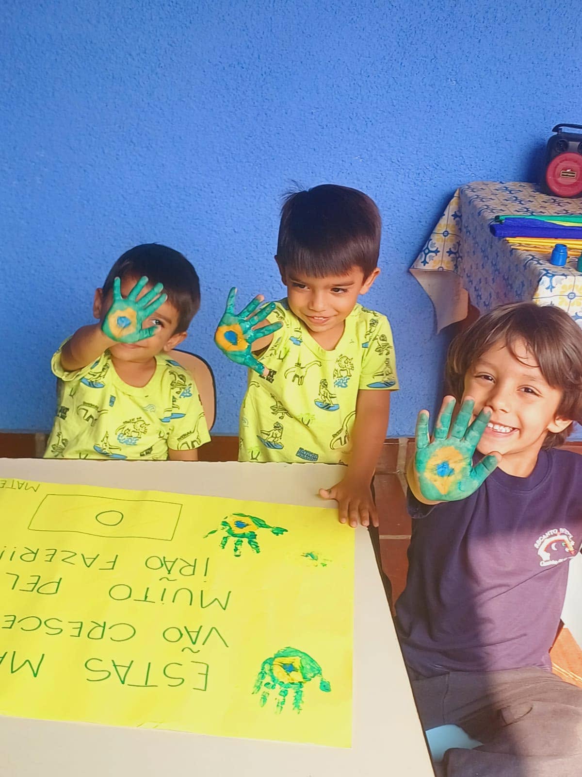 Meninos mostrando as mãos pintadas de verde e amarelo