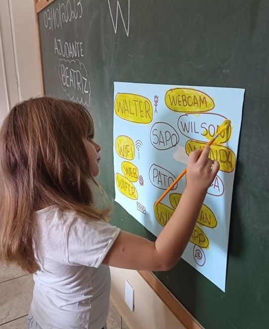 Menina circulando palavras num cartaz na lousa